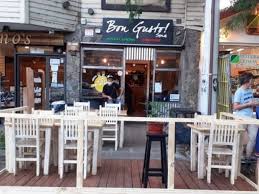 Bon Gusto - Fachada de pizzería Bon Gusto, con puerta de vidrio de entrada y en la vereda mesas y sillas blancas.