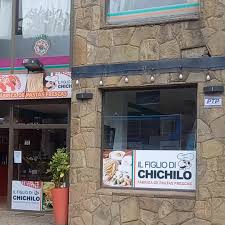 Chichilo - Fachada de comercio con paredes recubiertas en piedras y ventanal y puerta amplia de vidrio, tiene un cartel con el nombre Chichilo.