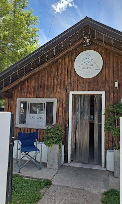 Doña Aurora - Fachada de un comercio en forma de cabaña con paredes de madera y techo a dos aguas. En la parte superior el logo de Rotisería Doña Aurora.
