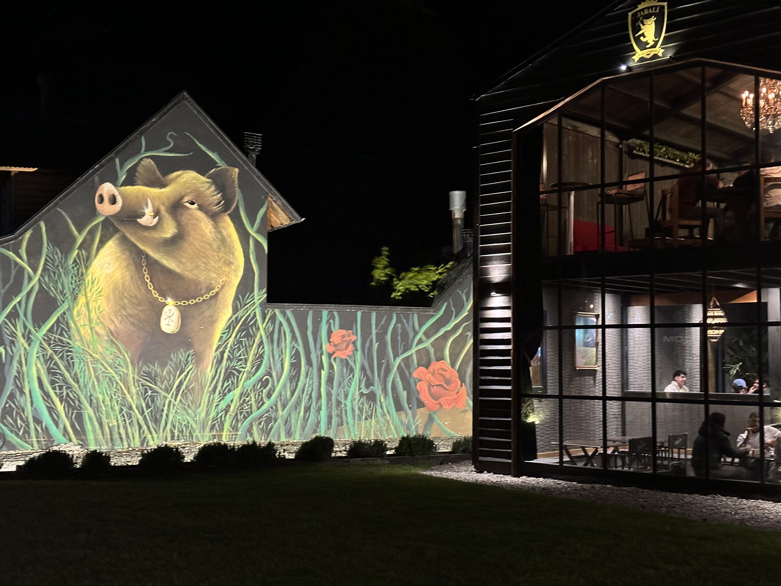 Jabalí - Fachada de ingreso a restaurante Jabalí, edificio construido en hierro negro con grandes ventanales y buena iluminación, en la pared lindera un gran dibujo de un jabalí.