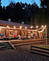 Mesta - Imagen de comercio realizado totalmente en madera estilo cabaña, con un deck del mismo material. Mucha luces para iluminar de noche.