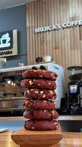 Mujica´s Café - Imagen de galletas sobre una tabla y mesa de madera, dentro de un negocio de café con el nombre Mujica´s café