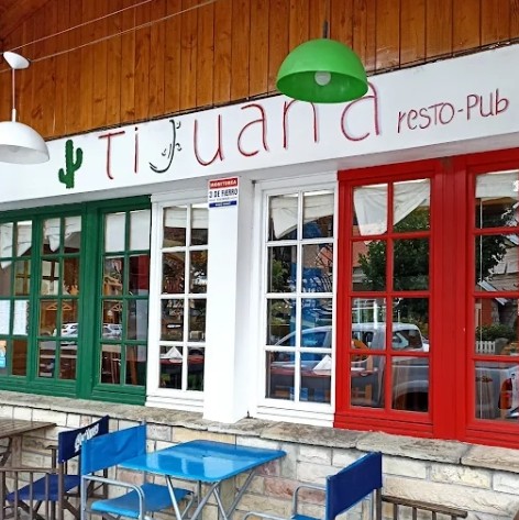 Tijuana tacos resto bar - Fachada de restaurante Tijuana, con ventanales de vidrios repartidos uno pintado de verde, otro de blanco y otro de rojo como la bandera de México. Sobre las ventanas paredes recubiertas en madera y debajo de las ventanas pared recubierta de piedra. 