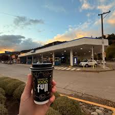 YPF Full centro - Estación de servicio en una esquina y una mano sosteniendo un vaso de café con la marca Full.