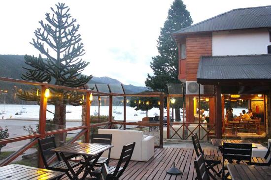 La Nueva Barra - Imagen de deck de madera con mesas y sillas, detrás el edificio del restaurante y vista del lago Lácar.