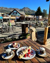 Wenüy Refugio de Historias - Imagen de una mesa servida con dos cafés espumosos y pastelería, en la base del centro de esquí Chapelco, de la confitería Wenuy.