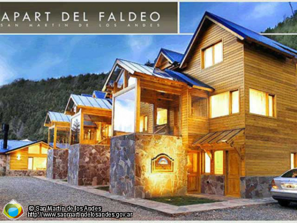 Un edificio de estilo moderno con revestimiento de madera y detalles en piedra. El edificio parece tener varios apartamentos, con grandes ventanales que ofrecen vistas panorámicas del paisaje circundante.