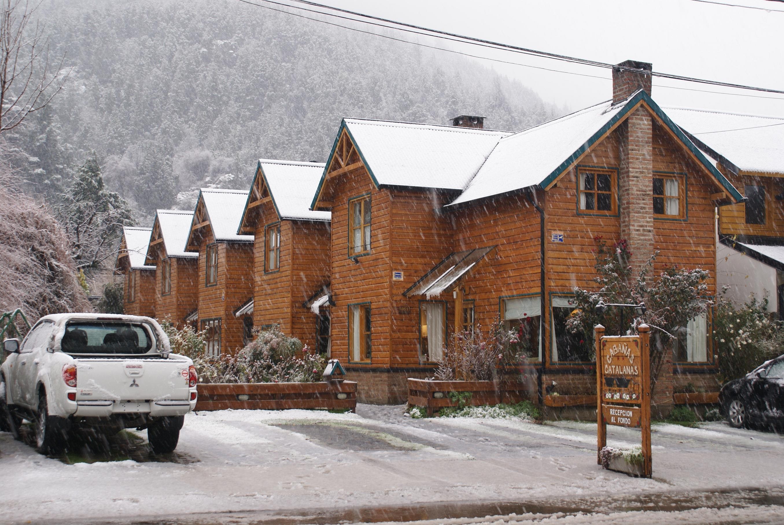 Cabañas de 2 plantas construidas en madera, con techos a 2 aguas cubiertos de nieve en un paisaje invernal.