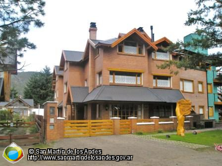 Edificio de dos pisos con un diseño arquitectónico distintivo,  construida con ladrillos a la vista de color terracota con techo, La fachada tiene  detalles en madera oscura, con varias ventanas y chimeneas.

