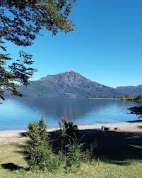 Vista de un paisaje con lago, montañas y bosque.