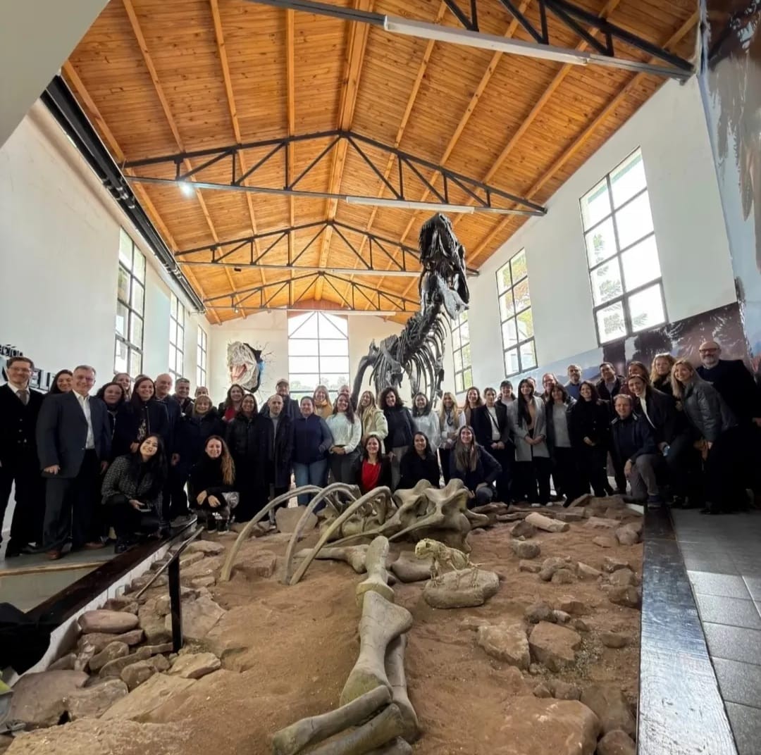 Grupo de personas posando para la foto. Delante de ellos restos de un dinosaurio en exhibición. 